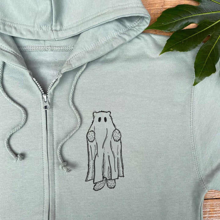 Light gray hoodie with a ghost design on a wooden surface with leaves.