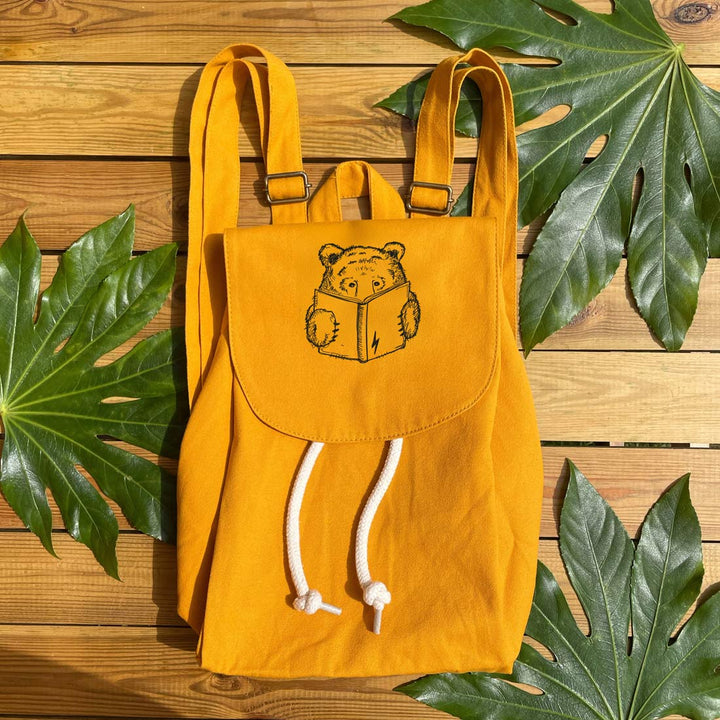 mustard backpack with bear reading a book
