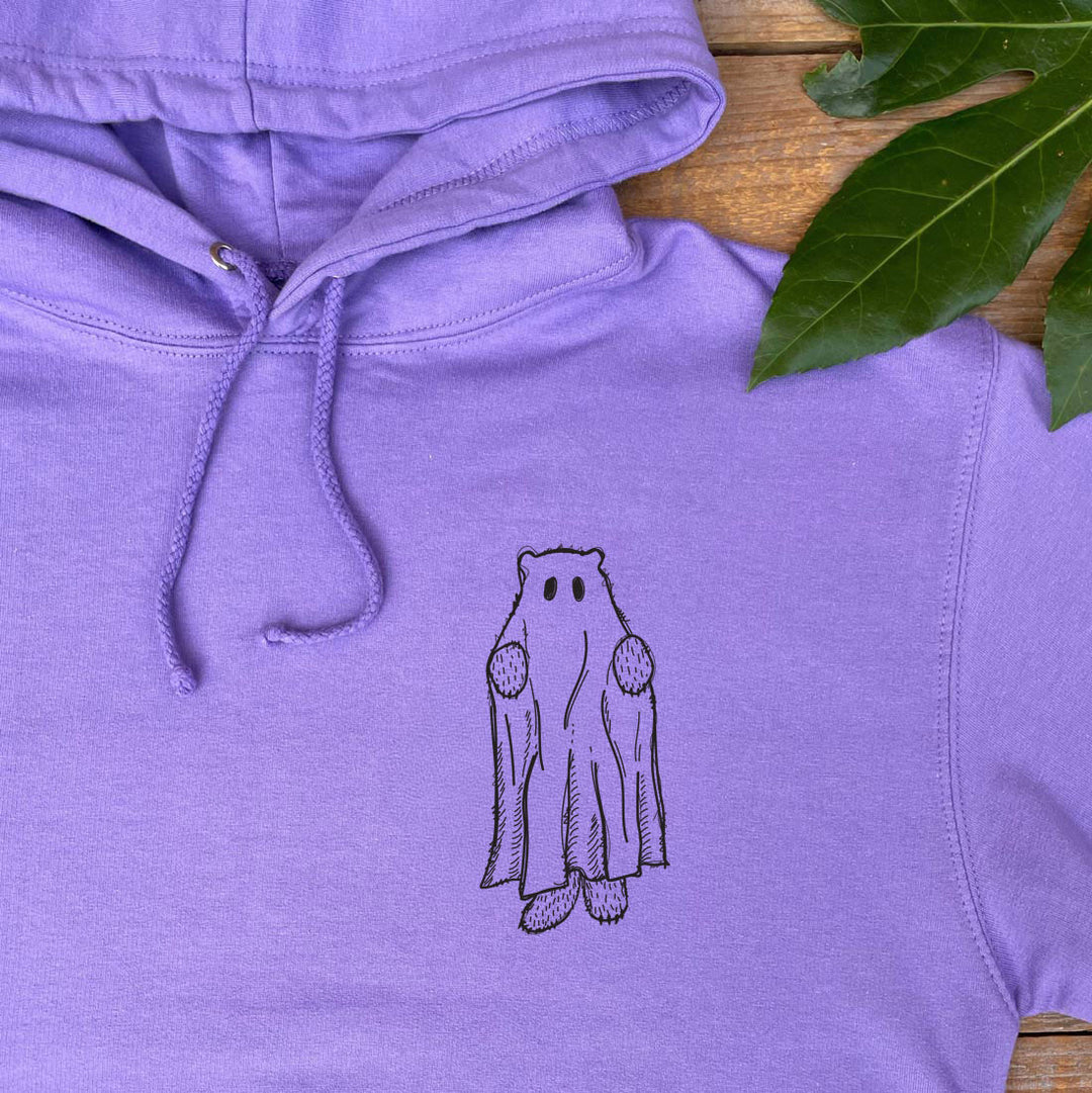 Purple hoodie with a ghost design on a wooden surface with leaves.
