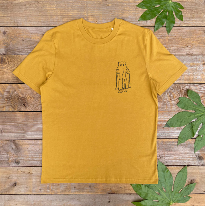Yellow t-shirt with a small graphic on a wooden surface with leaves.