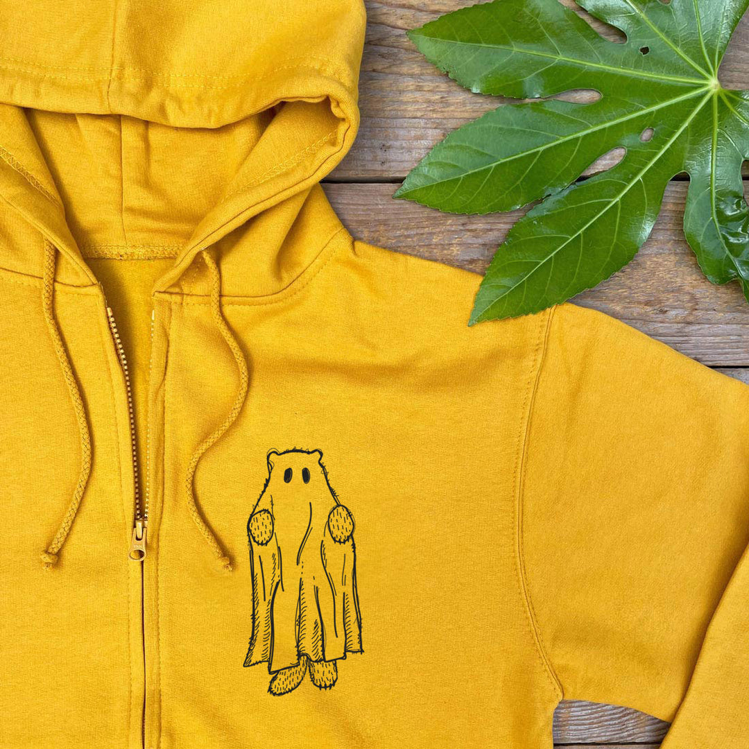 Yellow hoodie with a bear graphic on a wooden surface with leaves