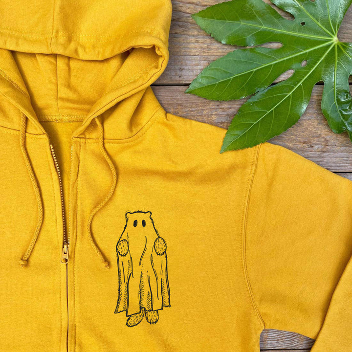 Yellow hoodie with a bear graphic on a wooden surface with leaves