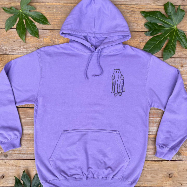 Purple hoodie with a small design on the chest, placed on a wooden surface with leaves around.