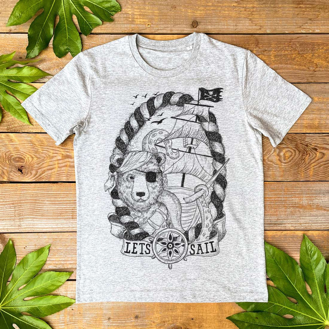 Gray t-shirt with a bear pirate design on a wooden surface with leaves.