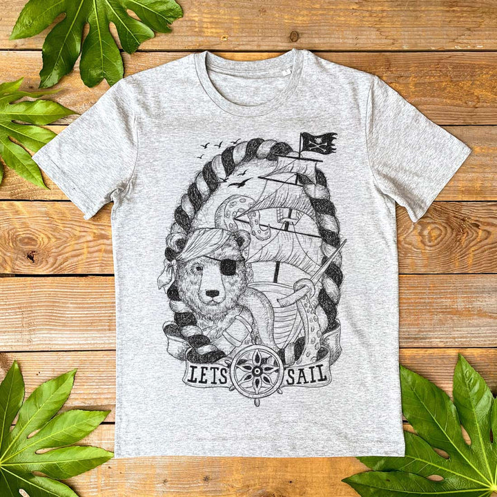 Gray t-shirt with a bear pirate design on a wooden surface with leaves.