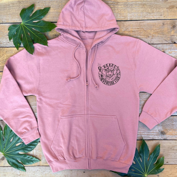 a dusy pink hoodie with a pocket print of bear adventure club