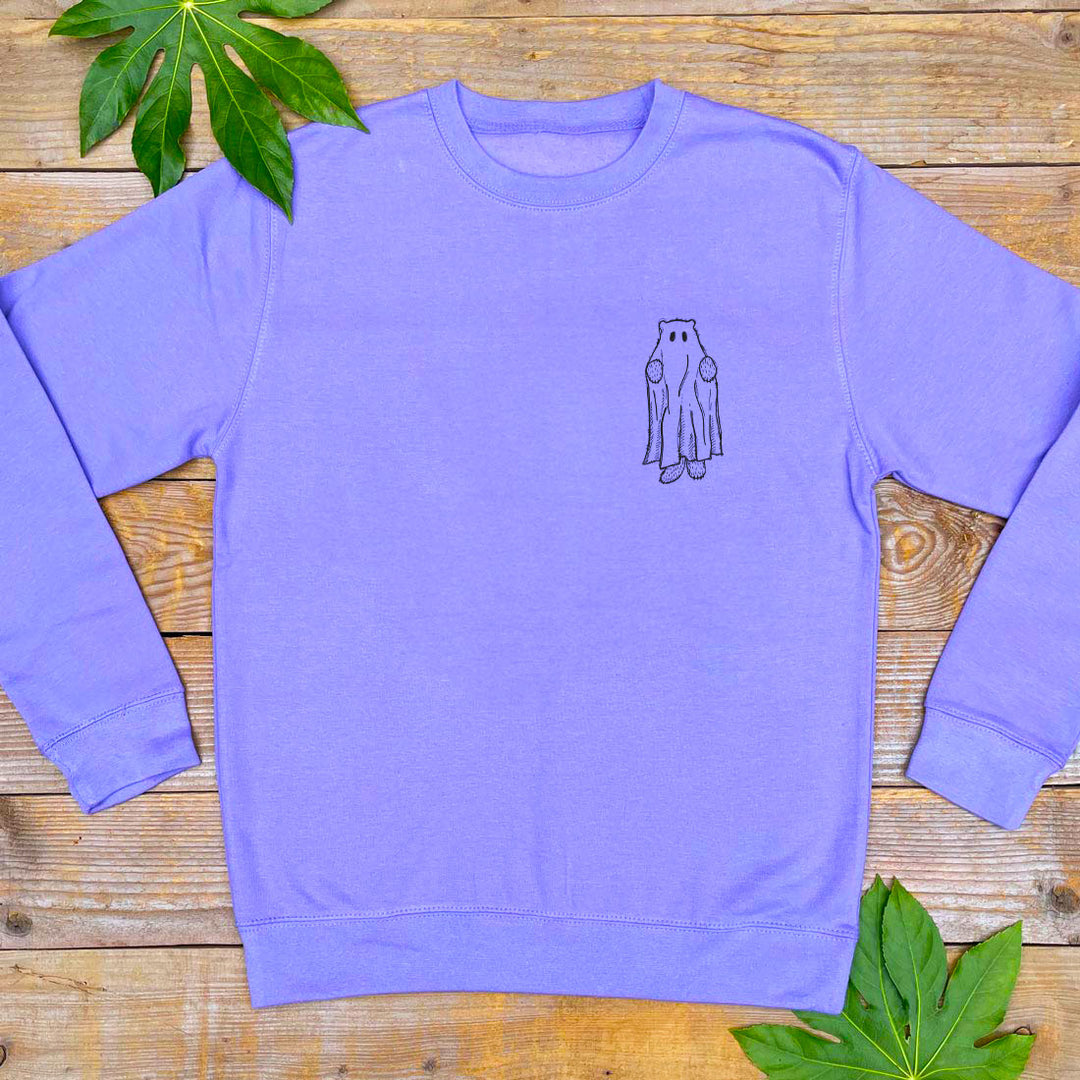 Purple sweatshirt with a small graphic on a wooden surface with leaves.