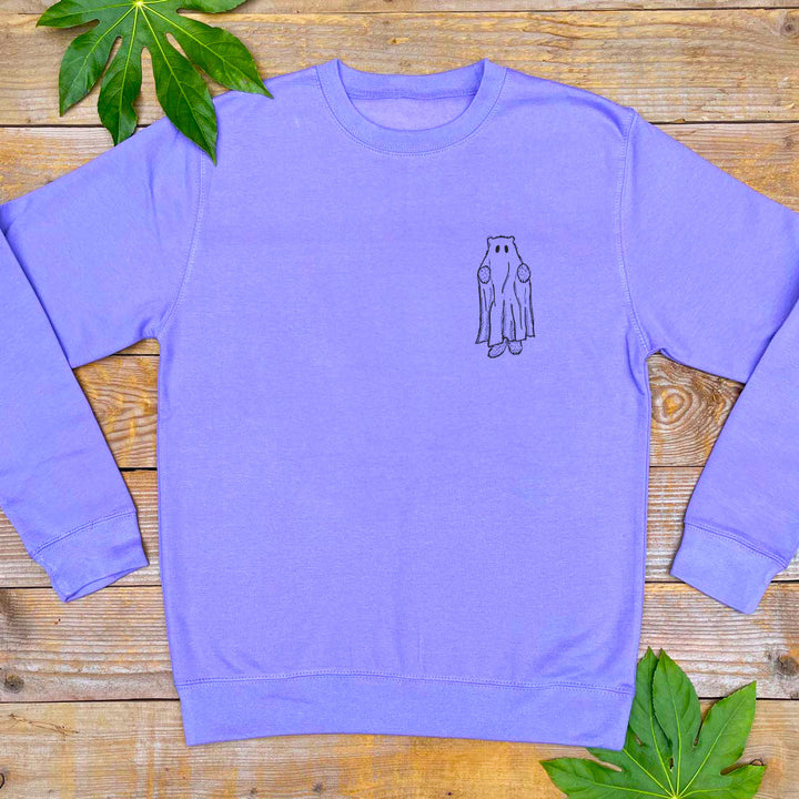 Purple sweatshirt with a small graphic on a wooden surface with leaves.