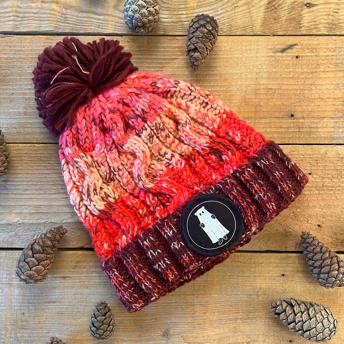 red and pink bobble hat with bear patch