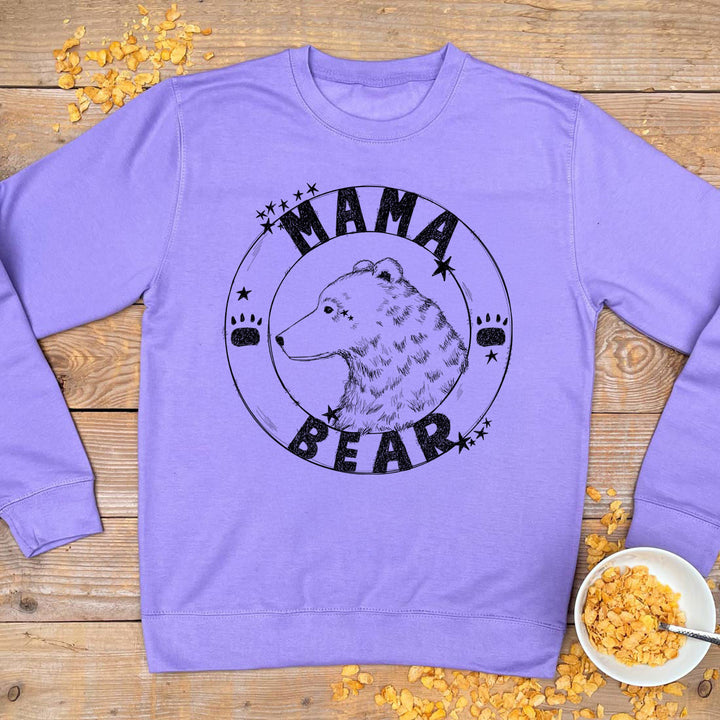 Purple sweatshirt with 'Mama Bear' graphic on a wooden surface with scattered cornflakes.