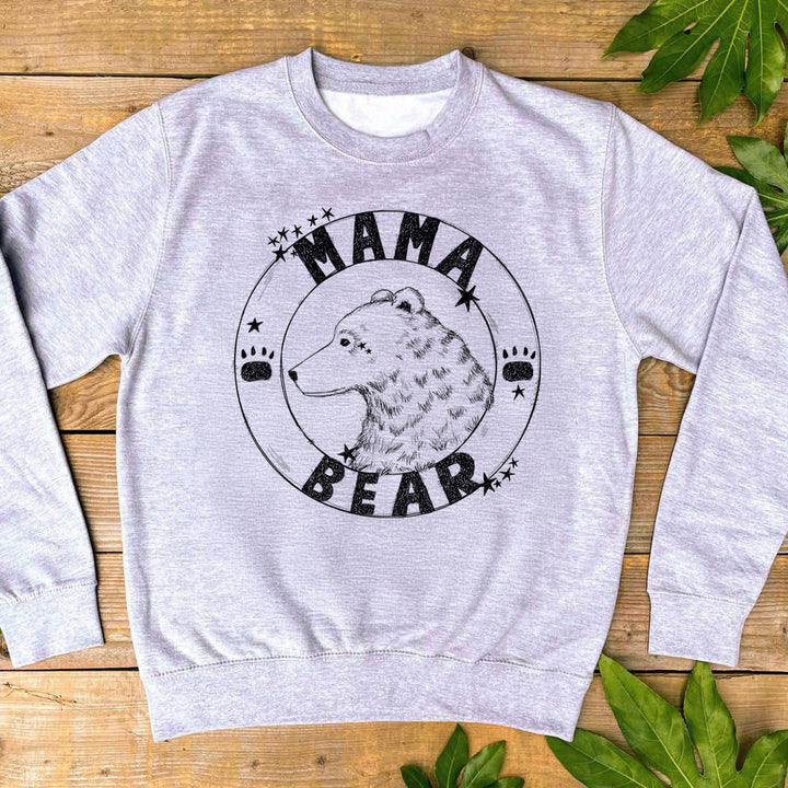 Grey sweatshirt with 'Mama Bear' graphic on a wooden surface with leaves.