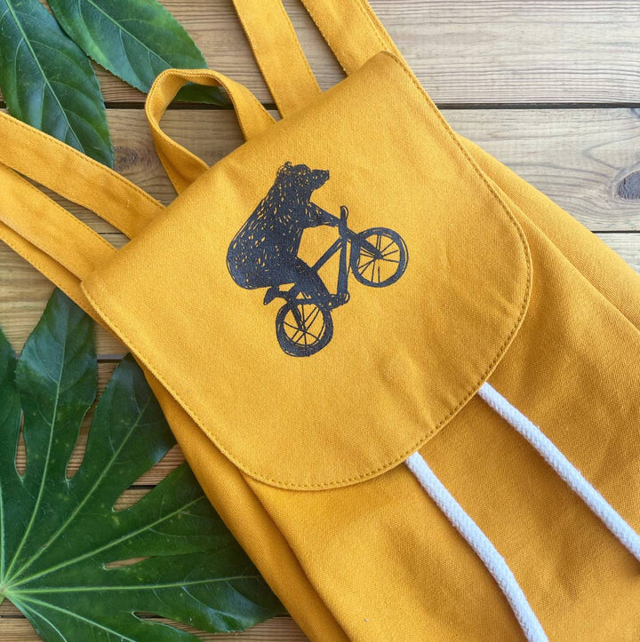 mustard backpack with bear riding bike design
