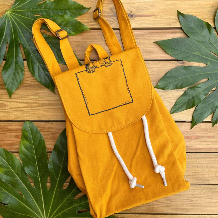 mustard backpack with bear peeking design