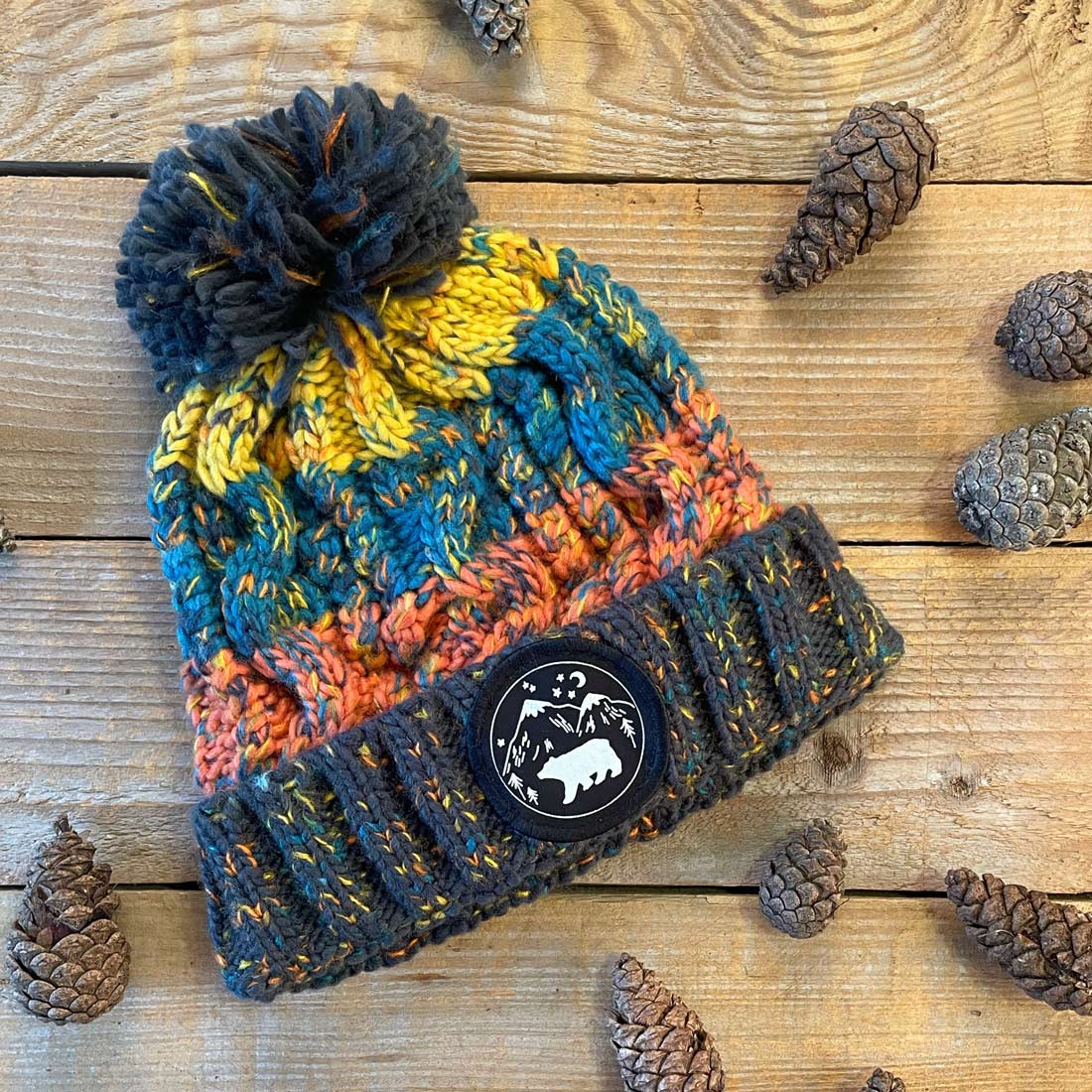 navy and orange chunky bobble hat with bear patch